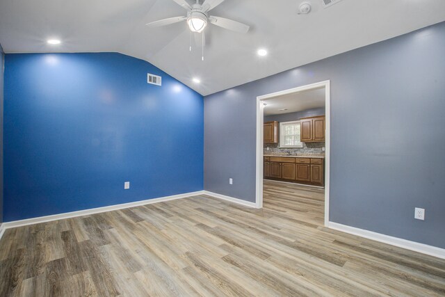 spare room with ceiling fan, sink, light hardwood / wood-style floors, and lofted ceiling