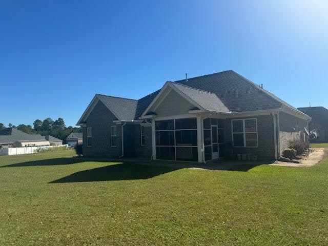 back of house with a lawn and a sunroom