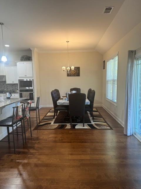 dining space featuring vaulted ceiling, ornamental molding, dark wood-type flooring, and a chandelier