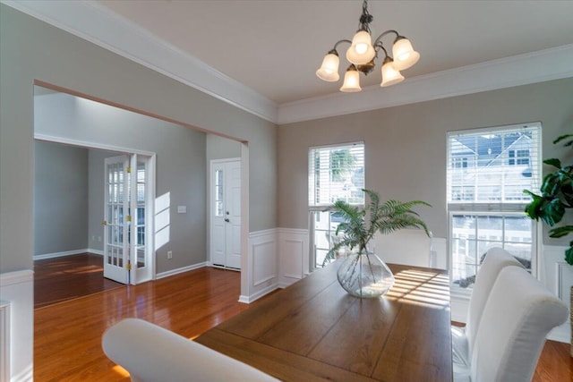 dining space with an inviting chandelier, hardwood / wood-style floors, and crown molding