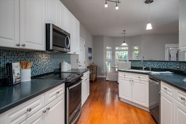 kitchen with appliances with stainless steel finishes, sink, pendant lighting, and white cabinets