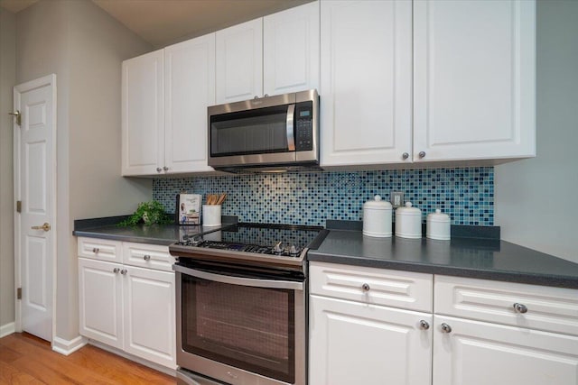 kitchen with appliances with stainless steel finishes, light hardwood / wood-style floors, decorative backsplash, and white cabinets