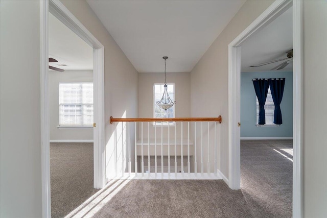 corridor with carpet flooring and a chandelier