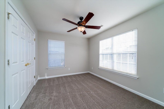 unfurnished bedroom featuring dark carpet, a closet, and ceiling fan