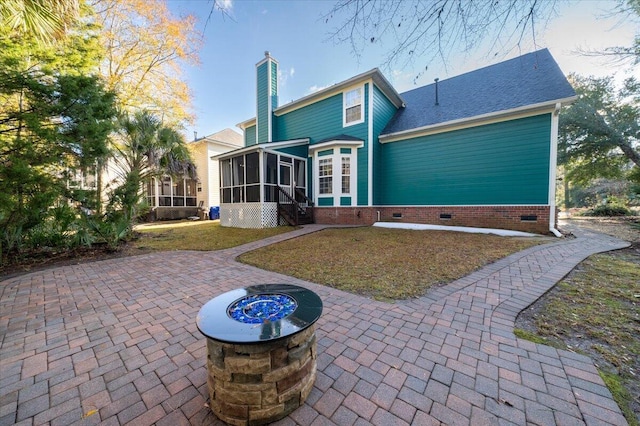 back of property featuring a sunroom, a patio, and a fire pit