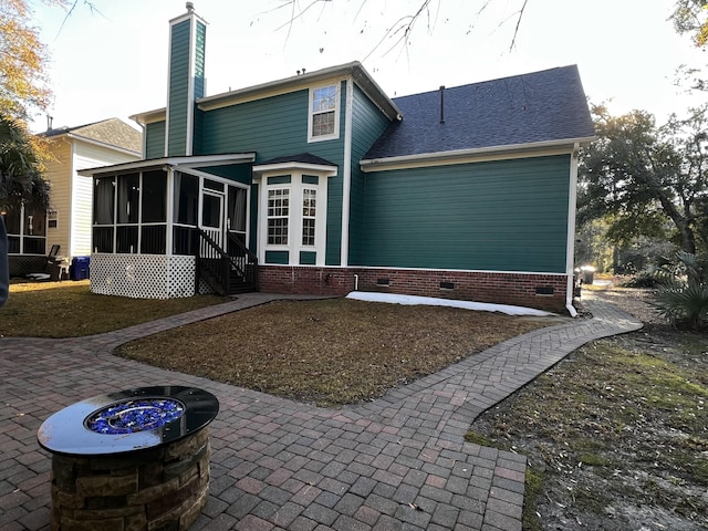 back of house with a sunroom, a patio area, and a fire pit