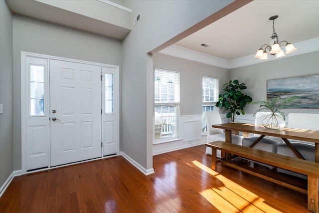 foyer entrance with an inviting chandelier, wood-type flooring, and ornamental molding