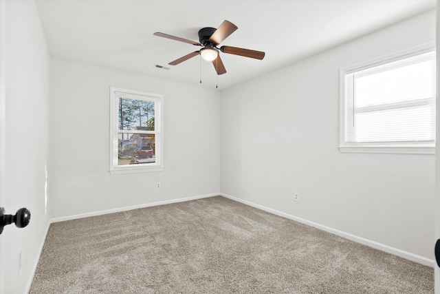 carpeted empty room with visible vents, a ceiling fan, and baseboards