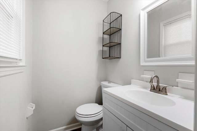 half bathroom with toilet, vanity, and baseboards