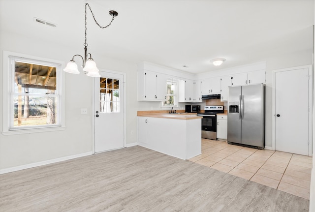 kitchen featuring a peninsula, stainless steel appliances, white cabinets, under cabinet range hood, and light wood-type flooring