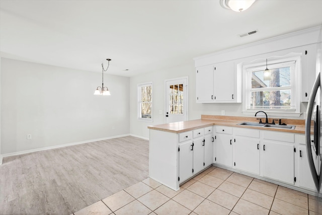 kitchen with visible vents, a sink, white cabinetry, light tile patterned flooring, and light countertops