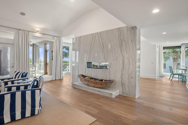 living room with a healthy amount of sunlight, light hardwood / wood-style floors, and vaulted ceiling