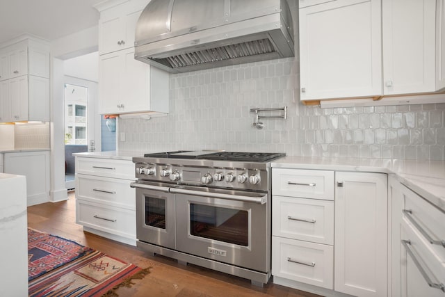 kitchen with white cabinets, extractor fan, dark hardwood / wood-style floors, range with two ovens, and decorative backsplash