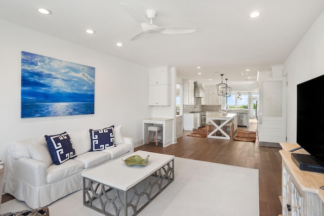 living room with ceiling fan with notable chandelier and dark hardwood / wood-style flooring