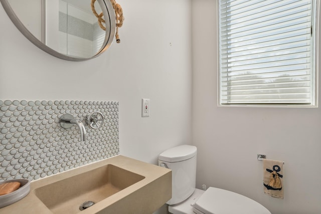 bathroom with sink, toilet, and decorative backsplash