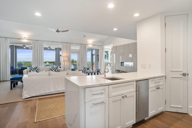 kitchen with light hardwood / wood-style floors, sink, white cabinetry, kitchen peninsula, and ceiling fan