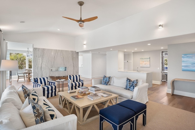 living room with ceiling fan, lofted ceiling, and light hardwood / wood-style floors