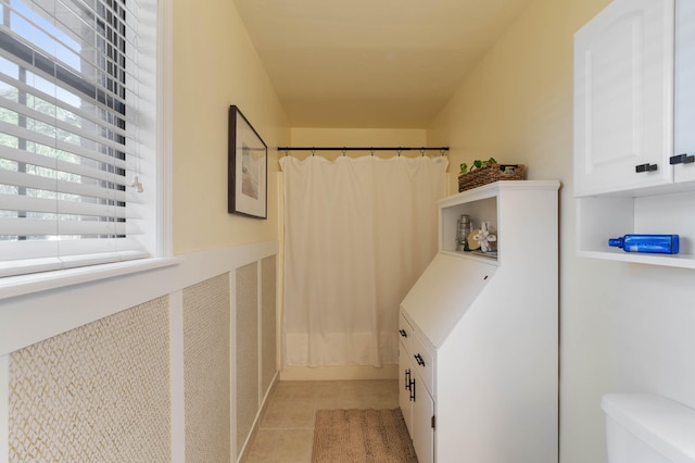 bathroom featuring toilet, curtained shower, and tile patterned flooring