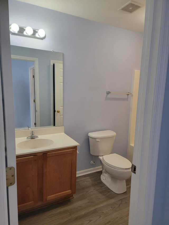 bathroom with wood-type flooring, vanity, and toilet