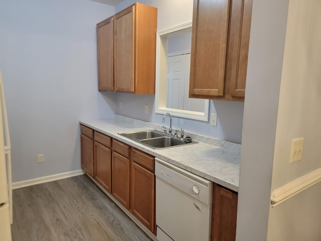 kitchen with white dishwasher, sink, and hardwood / wood-style flooring