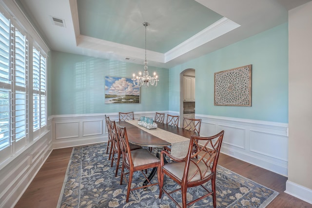 dining area with dark wood-style floors, a tray ceiling, and a chandelier