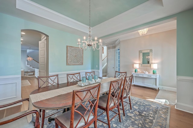 dining room with wainscoting, stairway, a tray ceiling, crown molding, and light wood-style floors