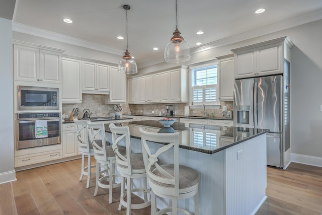 kitchen with appliances with stainless steel finishes, a sink, white cabinetry, and a center island