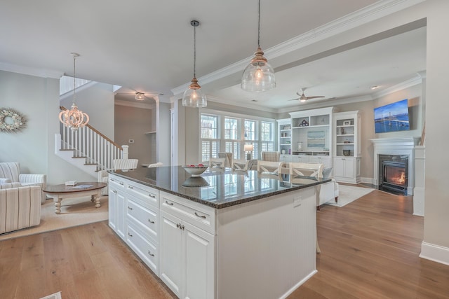 kitchen with light wood-style flooring, white cabinetry, open floor plan, a center island, and pendant lighting