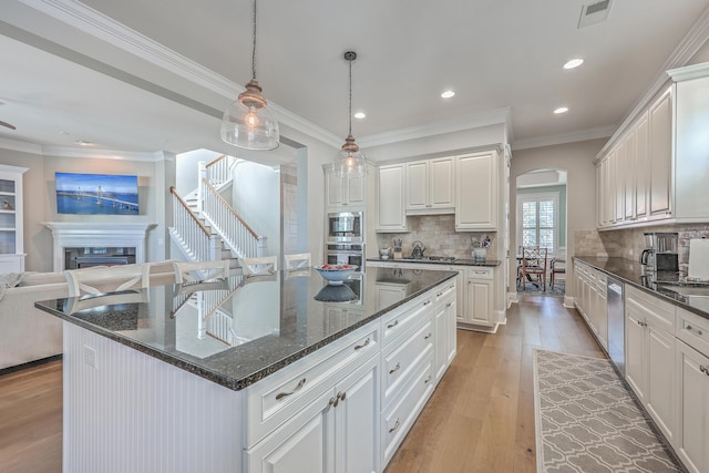 kitchen featuring arched walkways, pendant lighting, appliances with stainless steel finishes, open floor plan, and a kitchen island