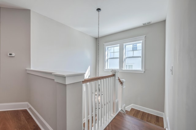 stairs with baseboards, visible vents, and wood finished floors