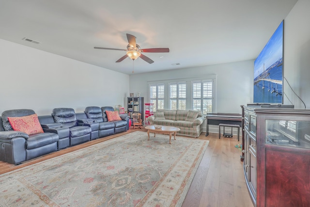 living room with light wood-style floors, visible vents, ceiling fan, and baseboards