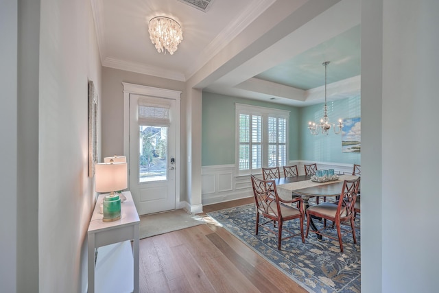 dining area featuring a wainscoted wall, plenty of natural light, and an inviting chandelier