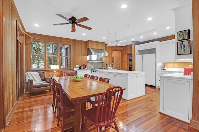 dining space featuring a ceiling fan, recessed lighting, light wood-style flooring, and wooden walls