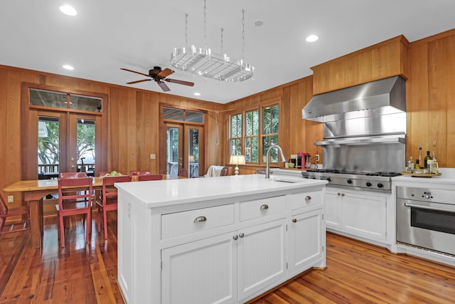 kitchen featuring appliances with stainless steel finishes, french doors, a sink, and wall chimney range hood