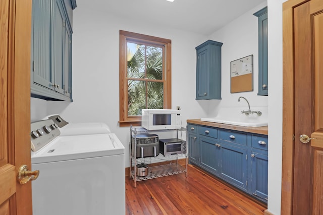 laundry room featuring cabinet space, dark wood-type flooring, separate washer and dryer, and a sink