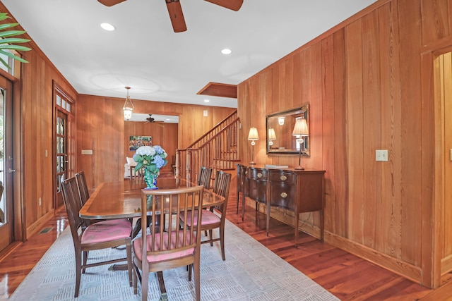 dining area featuring recessed lighting, stairway, ceiling fan, wooden walls, and wood finished floors