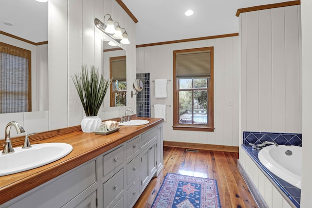 bathroom with double vanity, hardwood / wood-style flooring, crown molding, and a sink