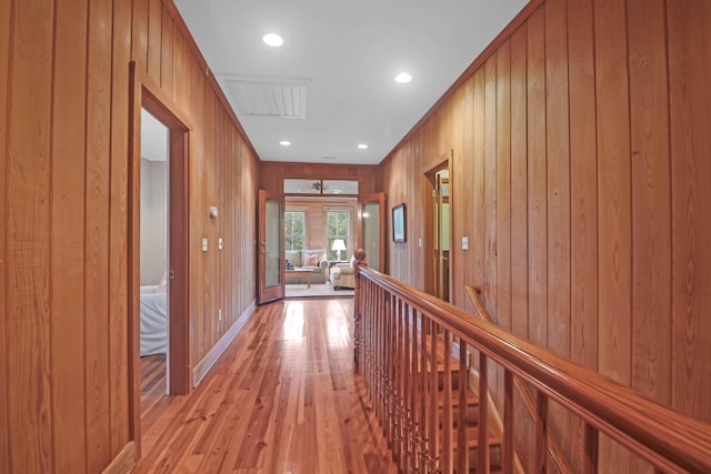 corridor featuring recessed lighting, wood walls, visible vents, an upstairs landing, and light wood-type flooring