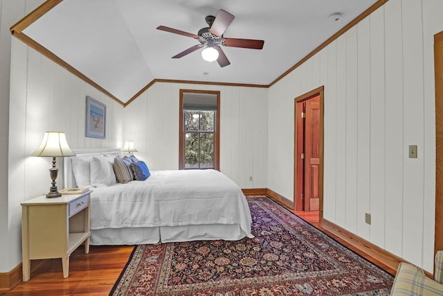 bedroom with baseboards, a ceiling fan, lofted ceiling, wood finished floors, and crown molding