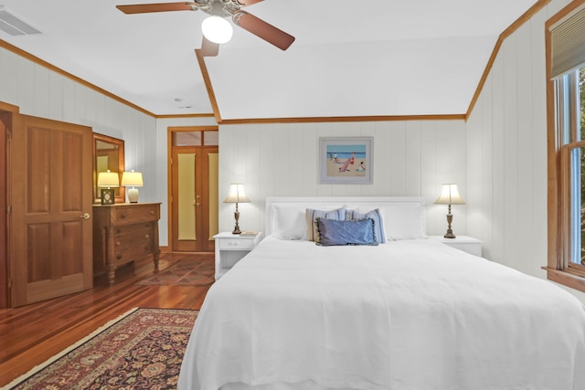 bedroom with a ceiling fan, visible vents, crown molding, and wood finished floors