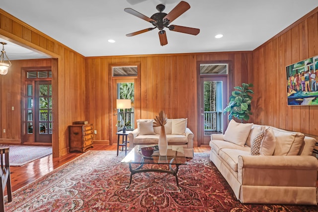 living area featuring wooden walls, a ceiling fan, and wood finished floors