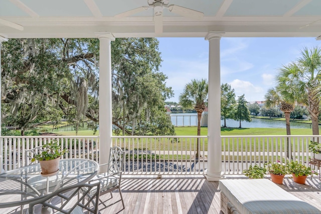 wooden terrace with a lawn, a ceiling fan, a water view, and covered porch