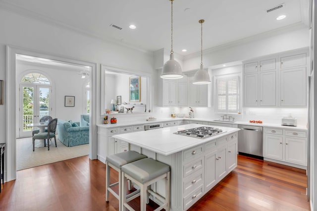 kitchen with a center island, a breakfast bar area, white cabinets, stainless steel appliances, and decorative light fixtures