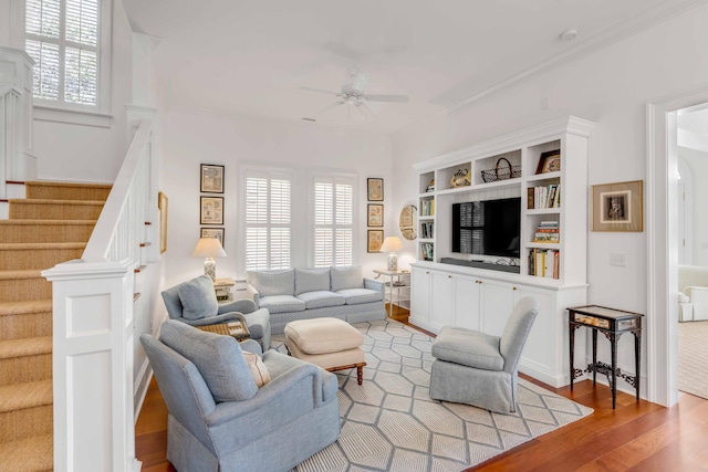 living room with stairway, wood finished floors, a ceiling fan, and built in features