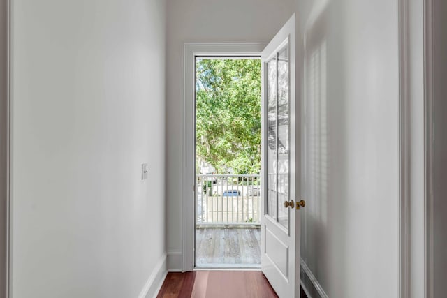 doorway with dark wood finished floors and baseboards