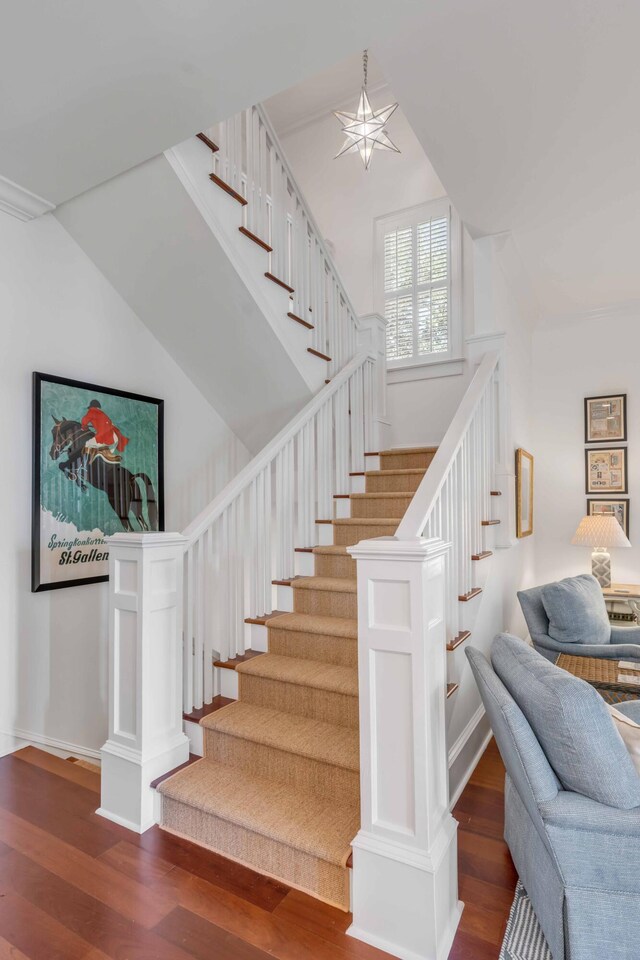stairway with wood finished floors and lofted ceiling