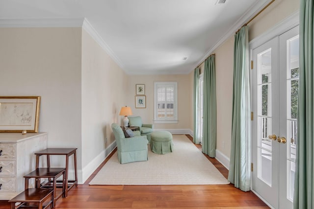 living area featuring crown molding, wood finished floors, and baseboards