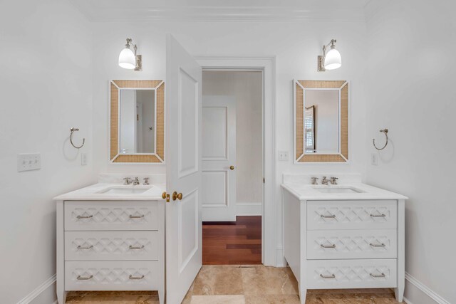 bathroom featuring two vanities, baseboards, and a sink