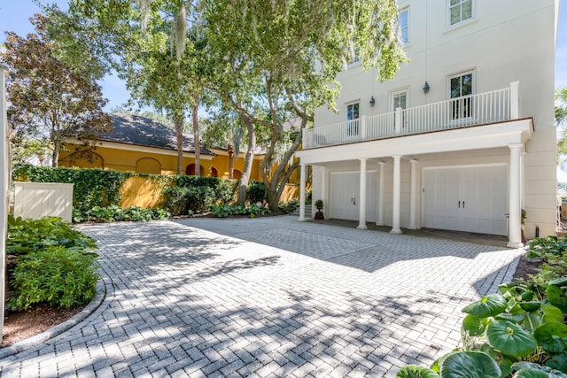 exterior space with a garage, stucco siding, decorative driveway, and a balcony