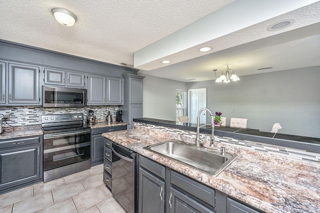 kitchen featuring stainless steel appliances, tasteful backsplash, a sink, and gray cabinetry